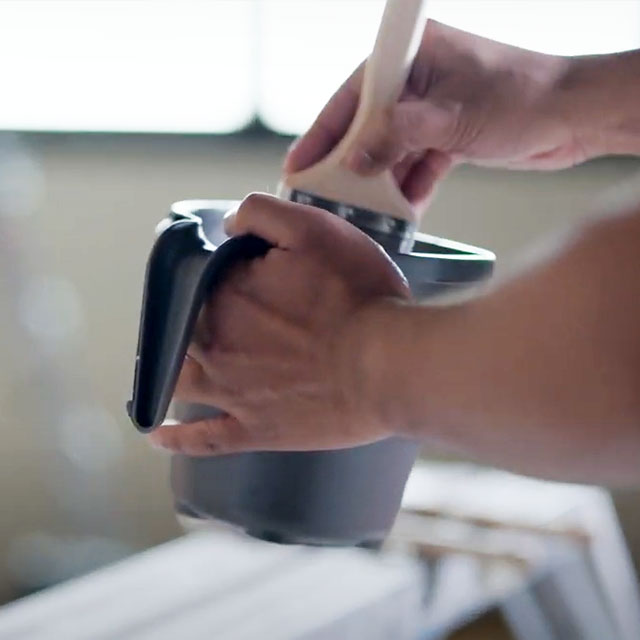 A painting contractor dips his paint brush into AURA® Interior paint. 