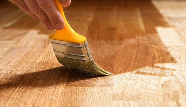 A pro painter refinishes a hardwood floor.