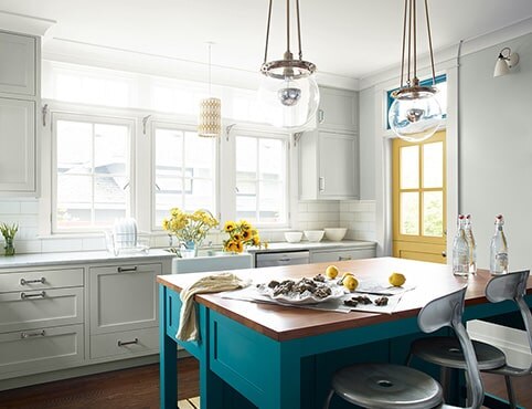 Bright, sun-drenched kitchen with painted yellow door and teal island