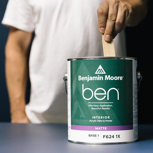 A painter stirs a can of ben Interior paint.