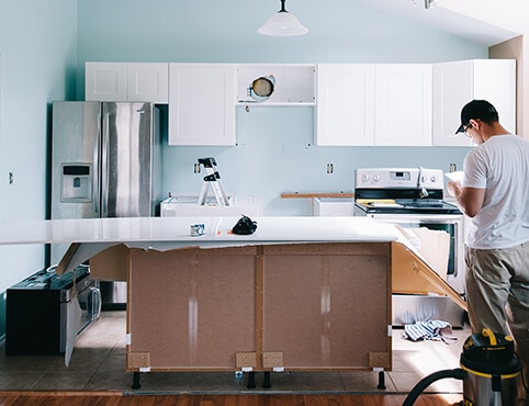 A contractor in the midst of a kitchen cabinet refinishing project