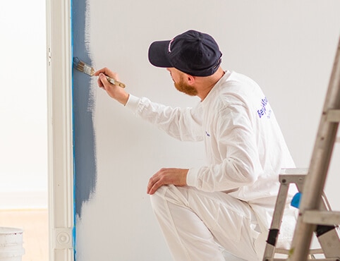 A contractor painting a wall