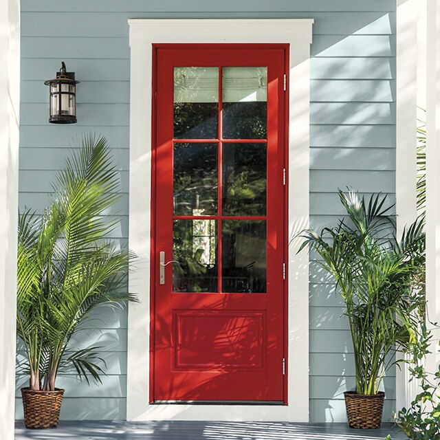 Une entrée accueillante avec une porte peinte en rouge et des plantes en pot
