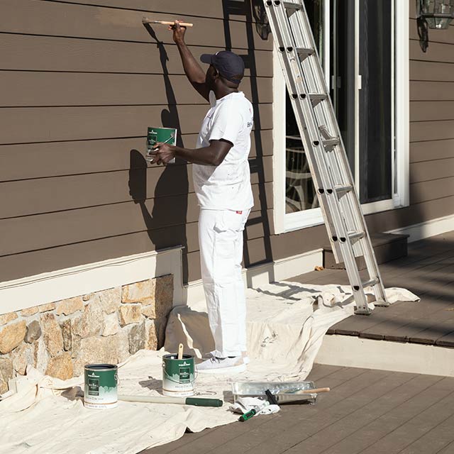 A contractor using a canvas drop cloth on an exterior paint job
