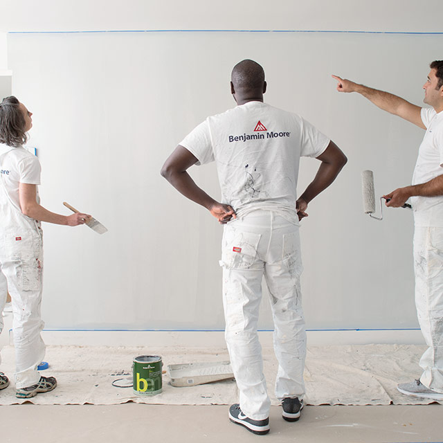 Trois entrepreneurs en peinture regardent un mur peint Trois entrepreneurs en peinture regardent un mur peint