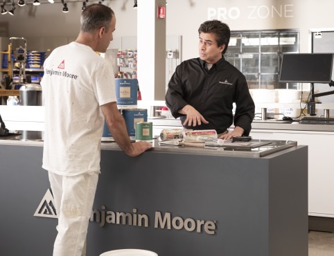 Contratista profesional de visita en una Pro Zone de Benjamin Moore, conversando sobre el catálogo de productos con un especialista minorista.