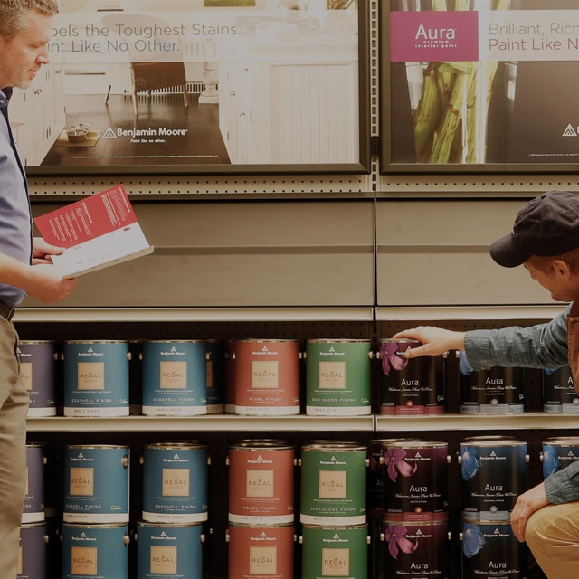 A store owner helps a paint contractor choose the best Benjamin Moore product.