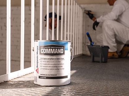 Un contenant de 3,79 L d’uréthane acrylique à base d’eau Command de Benjamin Moore à proximité d’un peintre qui rafraîchit un garde-corps blanc. Un contenant de 3,79 L d’uréthane acrylique à base d’eau Command de Benjamin Moore à proximité d’un peintre qui rafraîchit un garde-corps blanc.