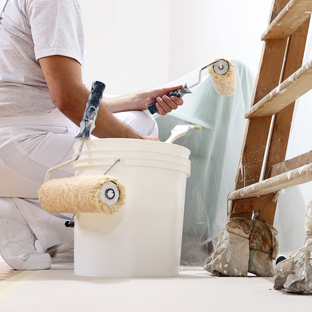 A Benjamin Moore contractor paints a white wall.