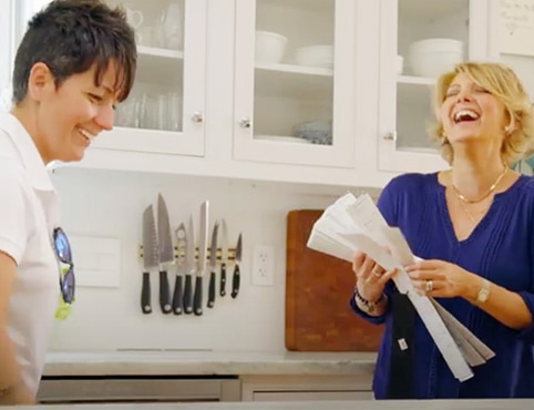 A painting contractor and a design consultant holding a color fan deck in a white-painted kitchen.