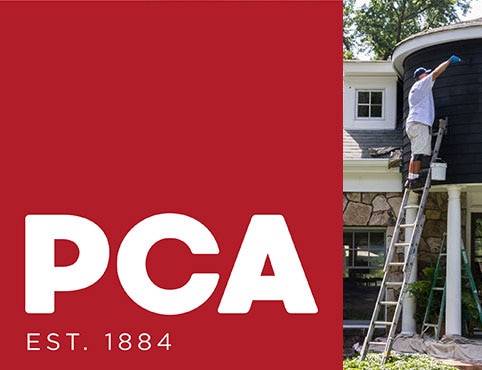 A painting contractor using a caulking gun on the exterior of a white painted house.