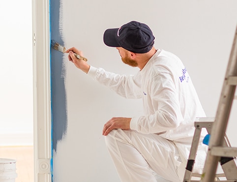 Un entrepreneur peintre Benjamin Moore applique de la peinture sur un mur