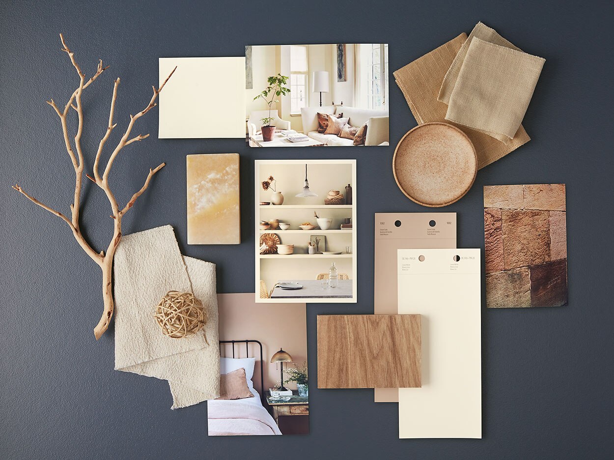 White and neutral paint chips, home interior photos and other natural accents lay atop a navy blue-painted surface.