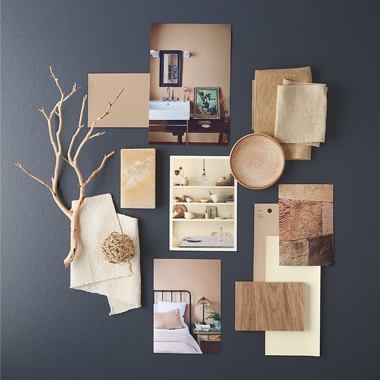 White and neutral paint chips, home interior photos and other natural accents lay atop a navy blue-painted surface.