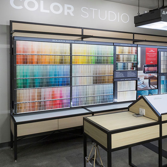 The interior of a Benjamin Moore store features a colour display and products on shelving.