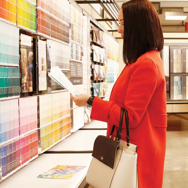 Varios clientes exploran opciones de color en una tienda Benjamin Moore.