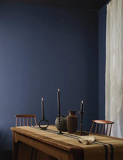 Un comedor pintado de Azul Zafiro oscuro con una mesa y sillas de madera rústica.