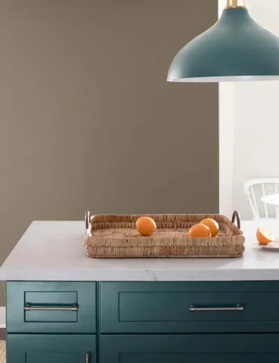 Gabinetes de cocina inferiores pintados en verde azulado claro con una encimera blanca, delante de una pared pintada en gris pardo y una pared blanca.