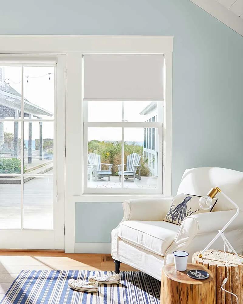 Una pared pintada de azul claro con marco blanco y un sillón blanco.