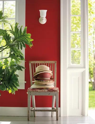 Una pared de entrada pintada de rojo con marcos blancos y una silla.
