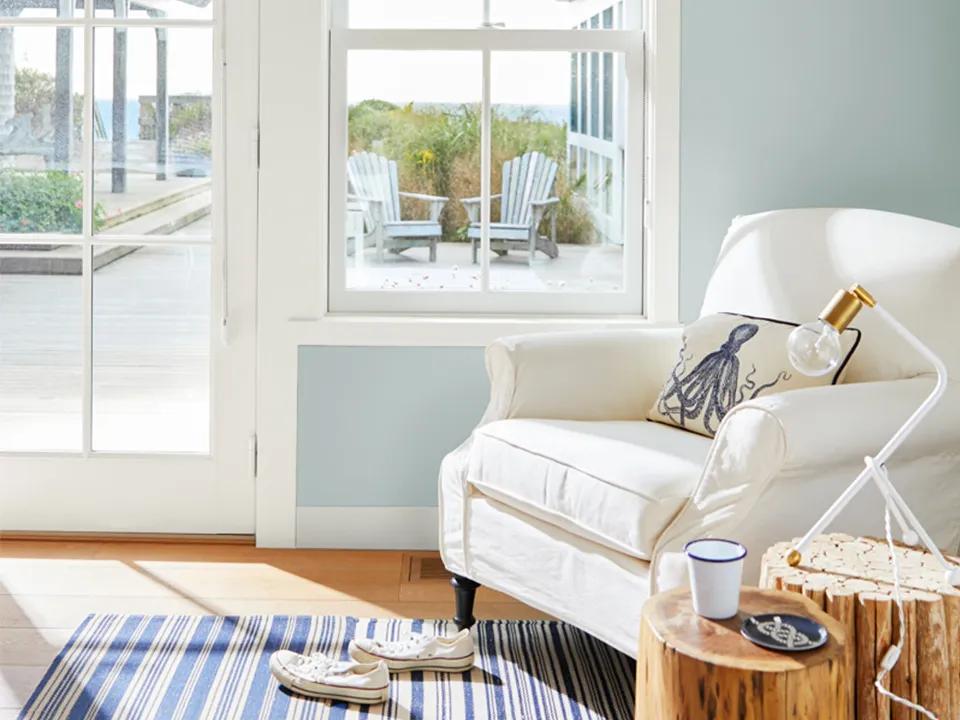Una pared pintada de azul claro con marco blanco y un sillón blanco.