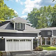 Miniatura: el exterior de una casa pintado de gris oscuro con las puertas del garaje, los marcos y las columnas pintados de blanco.