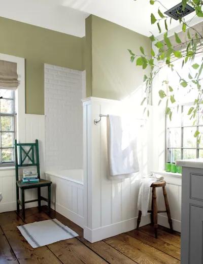 Un baño pintado de verde con paneles blancos.