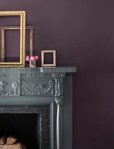 Una chimenea gris contra una pared pintada de púrpura.
