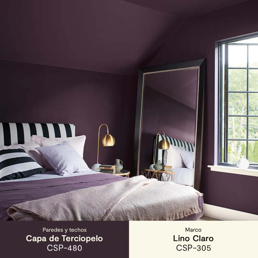 Una habitación con paredes pintadas de púrpura intenso, un techo abovedado, marcos blancos, y un cabezal rayado en blanco y negro.