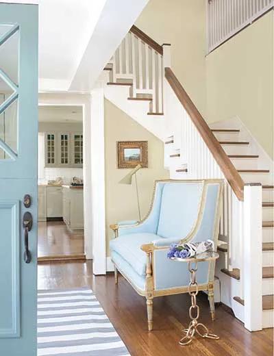 Un pasillo pintado de marrón claro con molduras y escaleras pintadas de blanco.