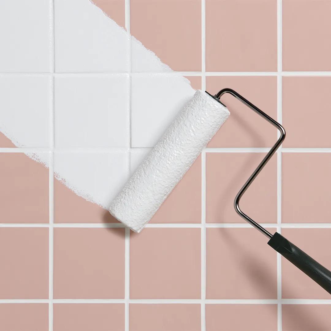 Primer plano del imprimador Insl-X® Stix® aplicándose con rodillo sobre una superficie de placa para techos rosa.