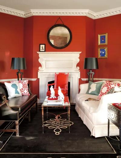 Una sala de estar pintada de rojo con una chimenea blanca.