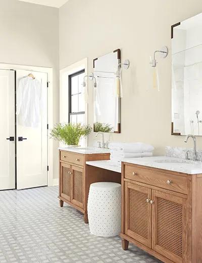 Un cuarto de baño con paredes pintadas de color Crema, marcos, puertas y techo de color Blanco, y dos tocadores de madera.