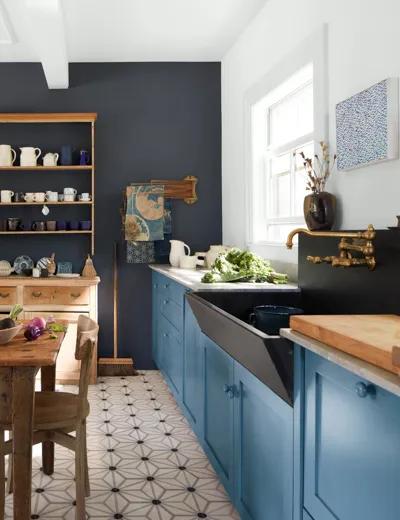 Una cocina con una pared pintada de azul marino oscuro, una pared blanca y gabinetes inferiores azules.