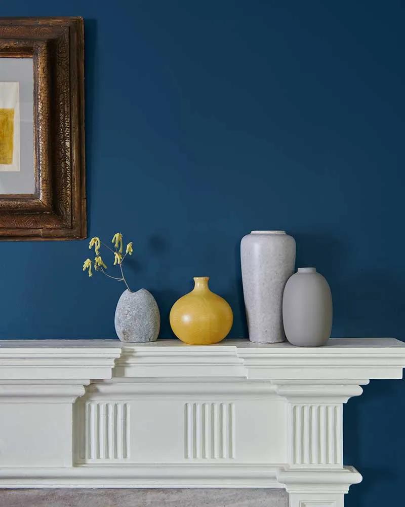 Una pared pintada de azul intenso y una chimenea blanca.