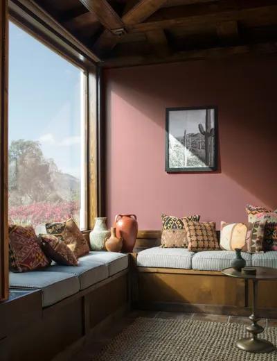 Una pared de sala de estar pintada de rojo parduzco junto a una gran ventana.
